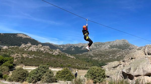 Persona cruzando una tirolina larga sobre un valle de granito en el parque de aventura