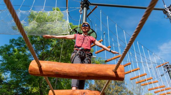 Participante cruzando un puente de troncos en un circuito de altura