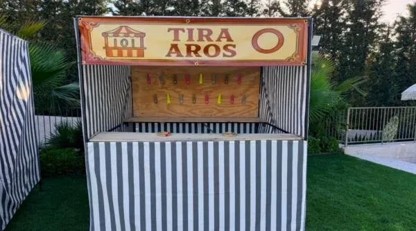 Caseta de tira-aros con su toldo de rayas en una feria de plantilla