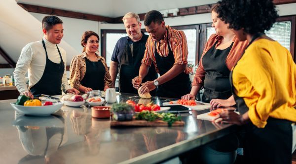 Equipos cocinando alrededor de una isla de acero en un concurso de cocina