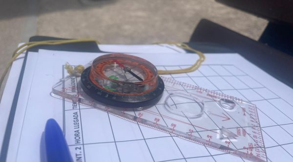 Brújula y regla sobre el mapa de una prueba de orientación en la sierra